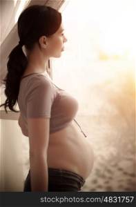 Side view of sad pregnant woman looking at window, expecting female at home, new life concept