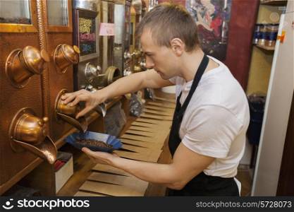 Side view of salesperson dispensing coffee beans into bowl at store