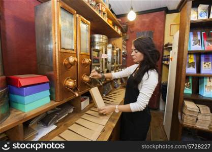 Side view of salesperson dispensing coffee beans into paper bag at store