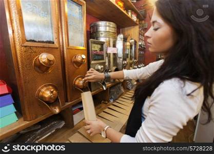 Side view of salesperson dispensing coffee beans into paper bag at store