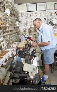 Side view of senior locksmith working in store