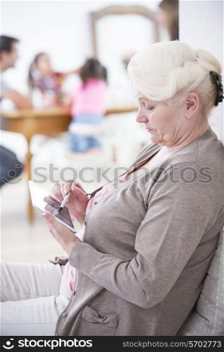Side view of senior woman using digital tablet at home