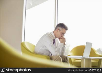 Side view of serious businessman looking at laptop in lobby