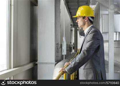 Side view of thoughtful male architect standing by railing in industry