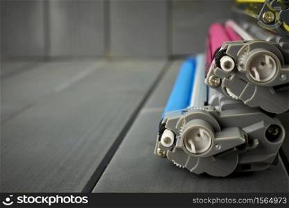 Side view of toner ink cartridges for an office laser printer on gray wooden background