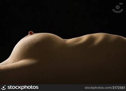 Side view of torso of nude Caucasian woman lying on back.
