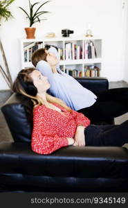 Side view of two young woman sitting on a leather sofa, relaxing
