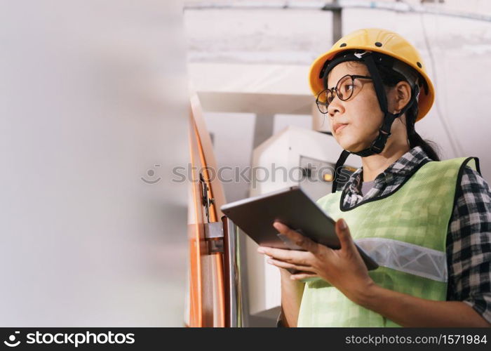 side view of woman engineer working on machine and check with tablet digital in the factory