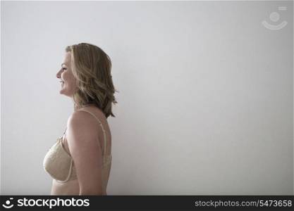 Side view of woman in bra smiling over gray background
