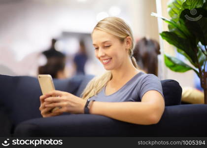 side view of women looking on mobile phone with smiling while sitting on sofa