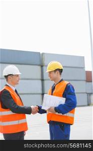 Side view of workers shaking hands in shipping yard