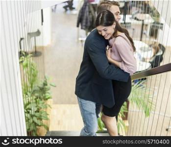 Side view of young business couple hugging on staircase