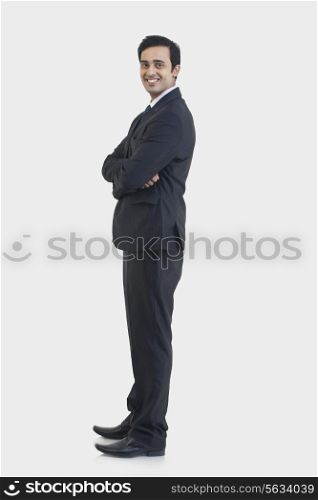 Side view of young businessman in suit standing against gray background