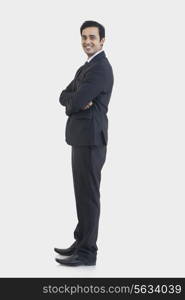 Side view of young businessman in suit standing against gray background