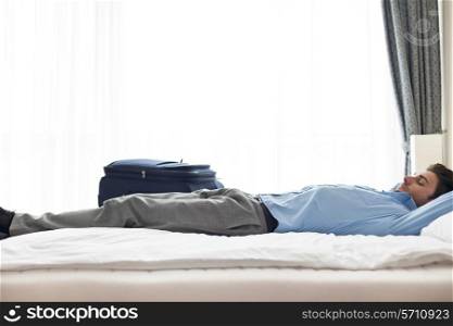 Side view of young businessman sleeping in hotel room