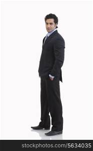 Side view of young businessman with hand in pocket against white background