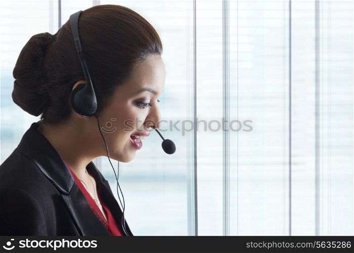 Side view of young female call center representative in office