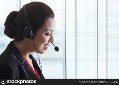 Side view of young female call center representative in office