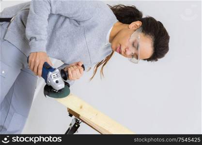 side view of young female carpenter cutting wood with tablesaw