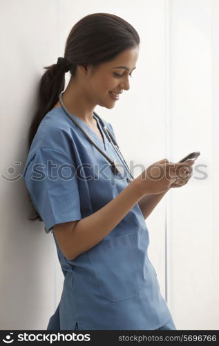 Side view of young female surgeon text messaging through cell phone