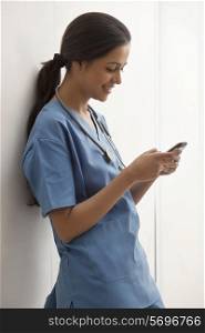 Side view of young female surgeon text messaging through cell phone