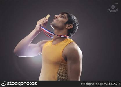 Side view of young male runner holding medal over black background