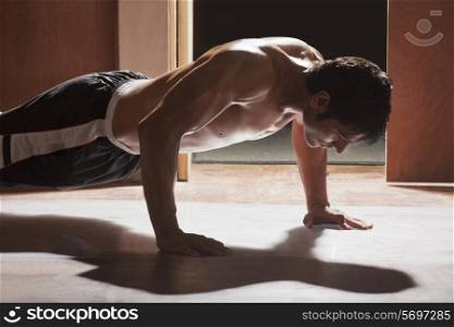 Side view of young man doing push-ups in gym