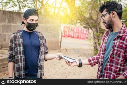 Side view of young man giving a surgical mask to another person, concept of a person giving a surgical mask, Two young people giving each other a surgical mask