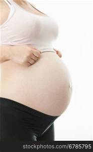 Side view of young pregnant woman showing big belly over white background
