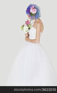 Side view of young woman in wedding dress with dyed hair against gray background