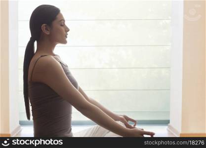 Side view of young woman meditating