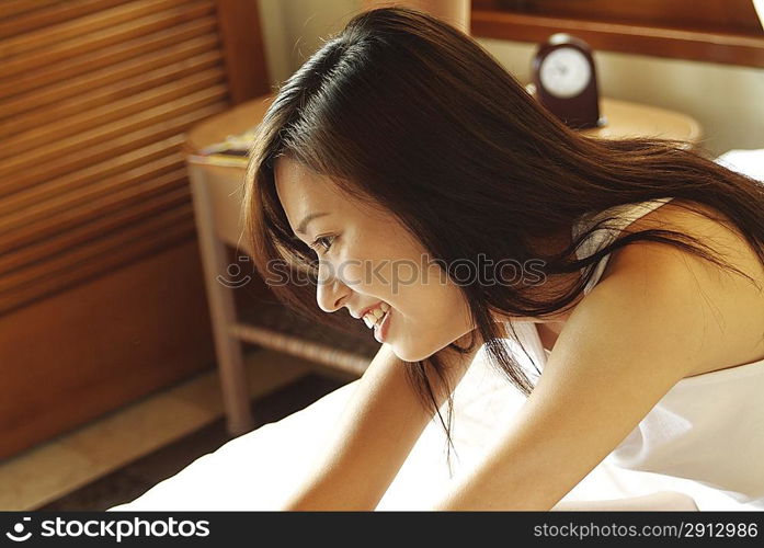 Side view of young woman sitting in bed
