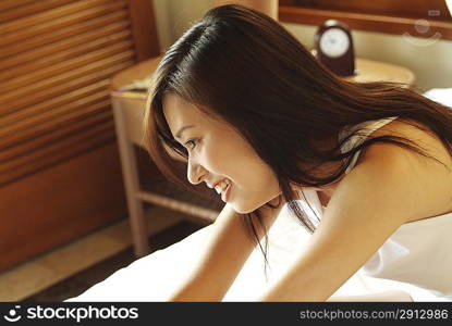 Side view of young woman sitting in bed