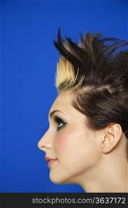 Side view of young woman with spiked hair over colored background