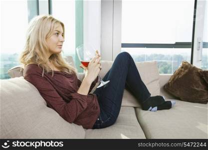 Side view of young woman with wine glass in living room at home