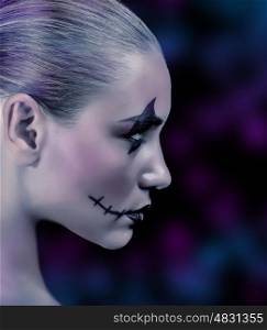 Side view of zombie girl with creepy makeup on blue and purple blurry background, night of horror, time for witches and vampire, Halloween holiday concept
