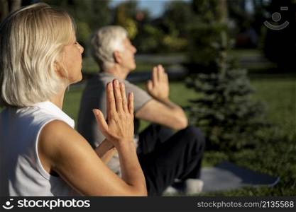 side view older couple practicing yoga outdoors