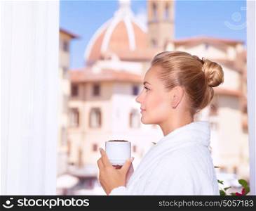 Side view on beautiful woman drinking coffee on the balcony and enjoying amazing European architecture, Italy, Florence