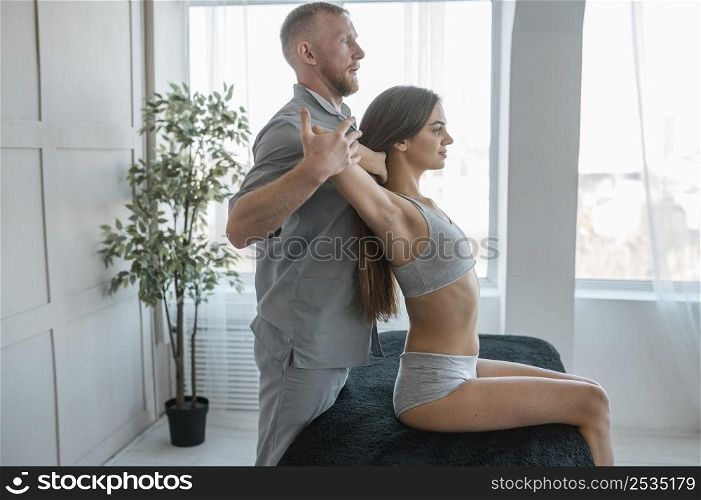 side view physiotherapist doing physical exercises with woman