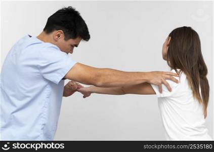 side view physiotherapist doing shoulder exercises with woman