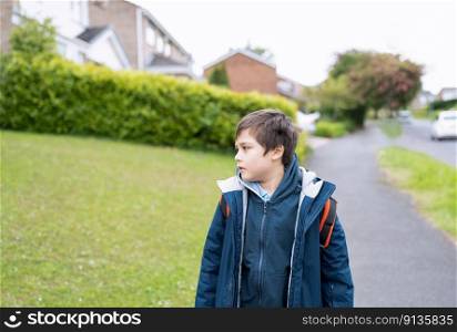 Side view portrait  kid looking out, Positive Child boy walking to school in the morning, School boy standing alone with blurry house and road