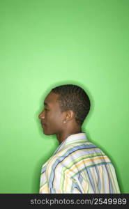 Side view portrait of African-American teen boy against green background.