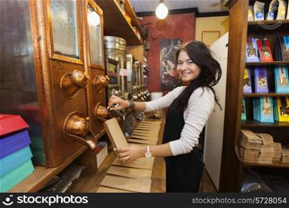 Side view portrait of female salesperson dispensing coffee beans into paper bag at store