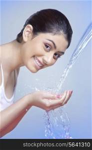 Side view portrait of happy woman washing face against blue background