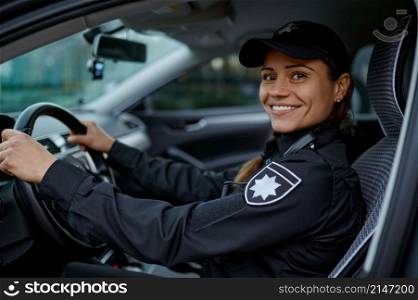 Side view portrait of smiling policewoman driving car. Female cop monitoring traffic law city order. Side view portrait police woman driving car