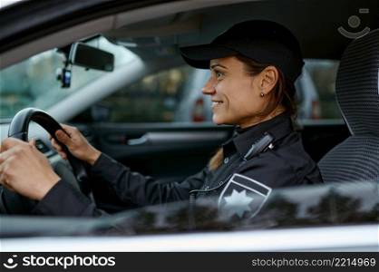 Side view portrait of smiling policewoman driving car. Female cop monitoring traffic law city order. Side view portrait police woman driving car