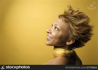 Side view portrait of smiling young African-American adult woman on yellow background.