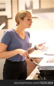 Side view portrait of women in her cooking dinner standing by stove and cooking on a gas hob white tiled wall with warm light