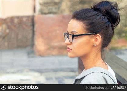 Side view portrait of young brunette business woman wearing eyeglasses outdoors. Portrait of young woman outdoor
