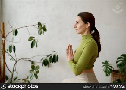 Side view portrait of young woman practicing yoga mindfulness technique sitting in lotus position, breathing and meditating. Side view portrait of young woman practicing yoga mindfulness technique